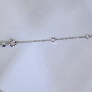 May include: A silver chain necklace with a lobster clasp and two jump rings. The chain is made of small, delicate links.