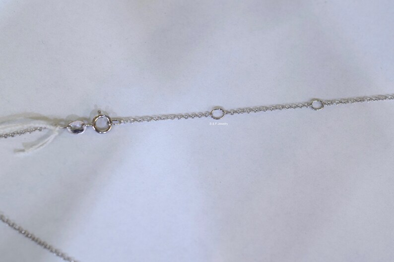May include: A silver chain necklace with a lobster clasp and two jump rings. The chain is made of small, delicate links.