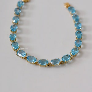 May include: A gold chain bracelet with oval-shaped blue topaz gemstones.