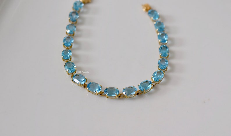 May include: A gold chain bracelet with oval-shaped blue topaz gemstones.