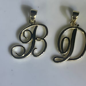 May include: Two gold-colored pendants, one shaped like the letter B and the other shaped like the letter D, both in a cursive font.
