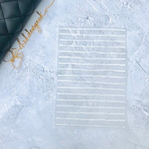 May include: A white, translucent sheet with a grid of white lines. The lines are uneven and have a slightly textured look.