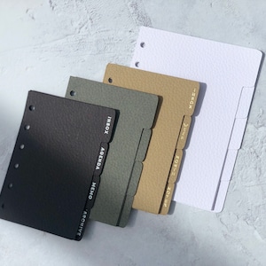 May include: Four different colored dividers for a personal planner. The dividers are black, gray, brown, and white. Each divider has a different tab with text on it. The black divider has the words "Inbox, Agenda, Memo, Archive". The gray divider has the word "Inbox". The brown divider has the words "Inbox, Week, Month, Notes". The white divider has the word "Inbox".
