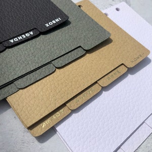 May include: Four different colored leather-bound notebooks with gold-colored tabs labeled "Inbox", "Agenda", "Jun 4-02", and "X-082".