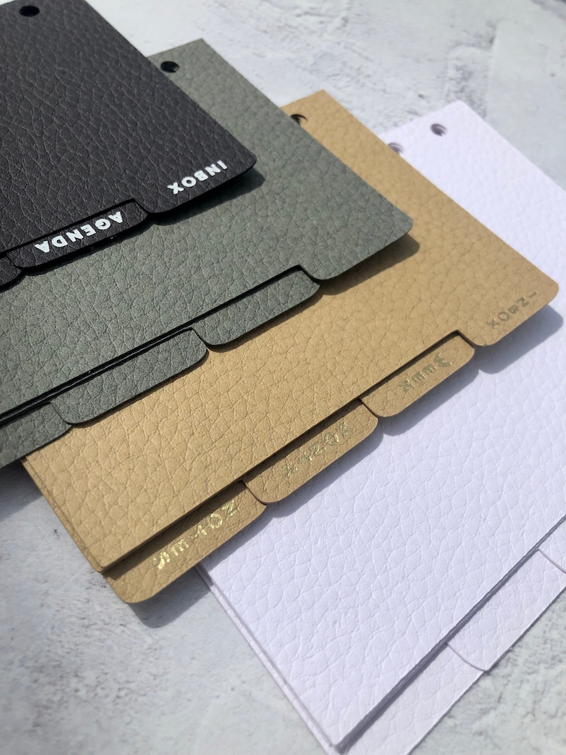 May include: Four different colored leather-bound notebooks with gold-colored tabs labeled "Inbox", "Agenda", "Jun 4-02", and "X-082".