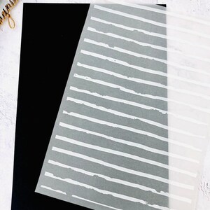 May include: A white sheet of paper with a pattern of white, uneven, horizontal lines on a black background.