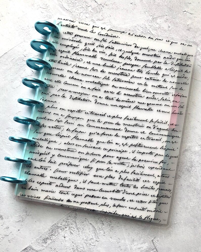 May include: A close-up of a page from a journal with handwritten text in black ink on a white background. The text is about the process of extracting a flammable spirit from a mineral. The page is bound with teal rings.
