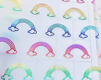 May include: A sheet of clear, translucent sticker paper with holographic rainbow stickers. The stickers feature a rainbow arch with clouds on either side.