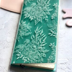 Puede incluir: Un diario verde con un dise&ntilde;o floral y una cubierta de pl&aacute;stico transparente. El diario tiene la fecha 2021 impresa en la cubierta.