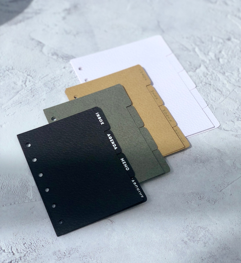 May include: Set of four black, green, brown, and white divider tabs for a disc bound planner. The tabs are labeled "Inbox", "Agenda", "Memo", and "Archive".