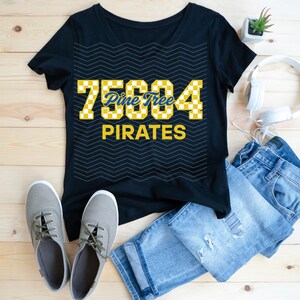 Puede incluir: Camiseta negra con un diseño amarillo y azul. La camiseta presenta el número "75604" en un patrón de cuadros, las palabras "Pine Tree" en escritura azul y la palabra "PIRATES" en letras amarillas. La camiseta se combina con vaqueros azules y zapatillas grises.