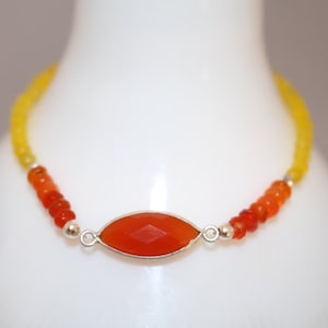 May include: A yellow and orange gemstone bracelet with a large, faceted carnelian gemstone in the center. The bracelet is made with small, round beads and silver accents.