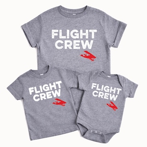 May include: Three gray t-shirts and a onesie with the text "FLIGHT CREW" in white. Each garment features a red airplane graphic. The shirts are short-sleeved, and the onesie has snap closures.
