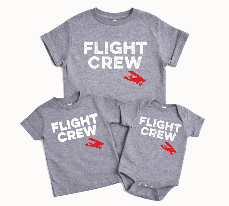 May include: Three gray t-shirts and a onesie with the text "FLIGHT CREW" in white. Each garment features a red airplane graphic. The shirts are short-sleeved, and the onesie has snap closures.