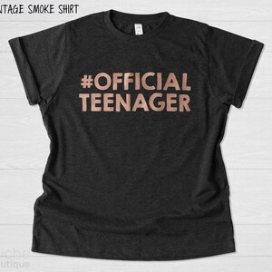 May include: A black t-shirt with the text "#OFFICIAL TEENAGER" in rose gold lettering.