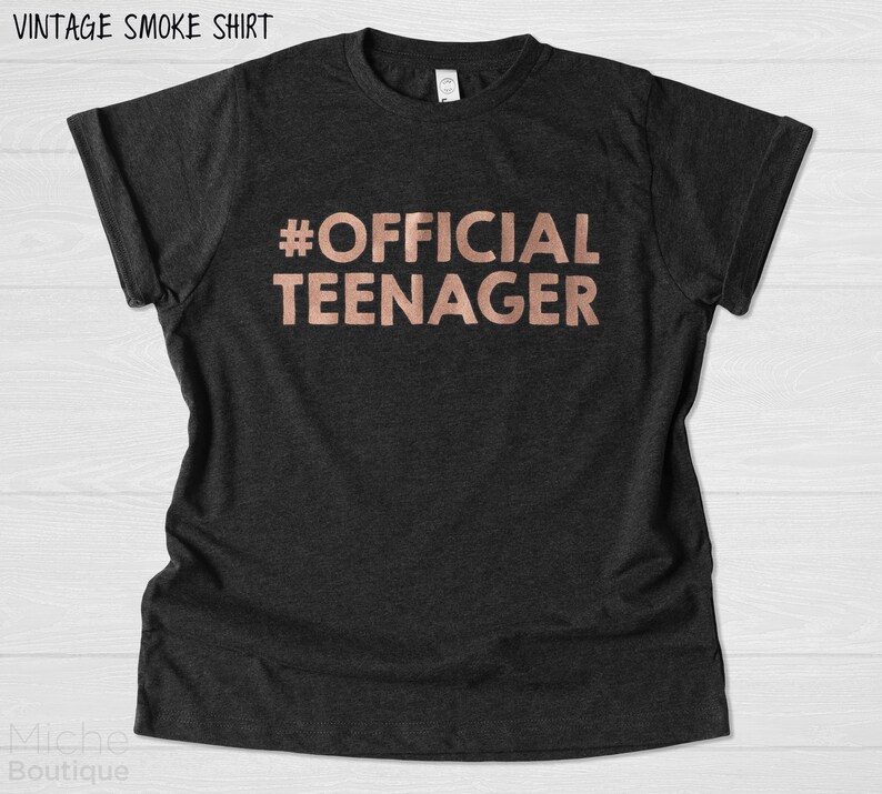 May include: A black t-shirt with the text "#OFFICIAL TEENAGER" in rose gold lettering.