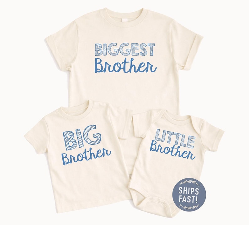 May include: Three cream-colored shirts with blue text. The shirts read "BIGGEST Brother", "BIG Brother", and "LITTLE Brother". The "LITTLE Brother" shirt is a onesie. A blue and white "SHIPS FAST!" sticker is in the image.
