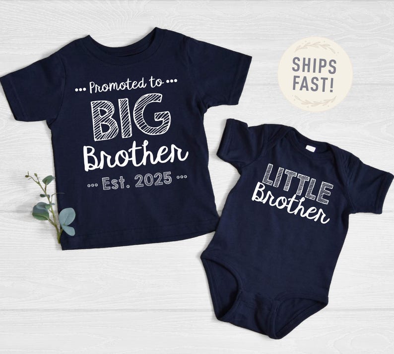 May include: Navy blue t-shirt with "Promoted to BIG Brother Est. 2025" in white text. A navy blue babygrow with "LITTLE Brother" in white text. Both items are baby and toddler apparel.