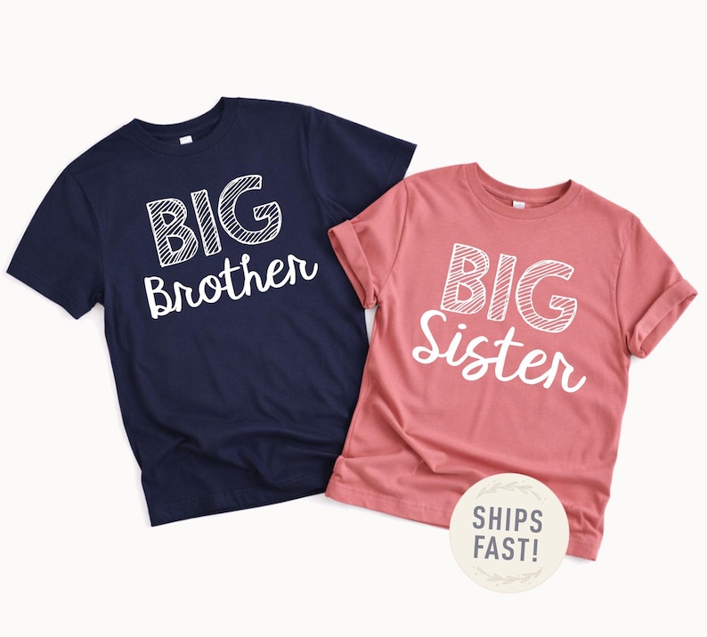 May include: Two short-sleeved t-shirts. One is navy blue with the words "BIG Brother" in white. The other is a dusty rose colour with the words "BIG Sister" in white. The shirts are likely for siblings.