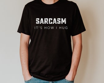 May include: A black t-shirt with white text that reads "SARCASM IT'S HOW I HUG".