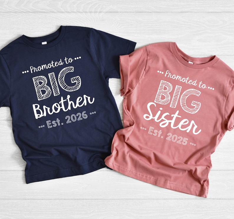 May include: Two t-shirts, one navy blue and one dusty rose, with white text. The navy shirt says "...Promoted to... BIG Brother ...Est. 2026...". The dusty rose shirt says "...Promoted to... BIG Sister ...Est. 2025...".