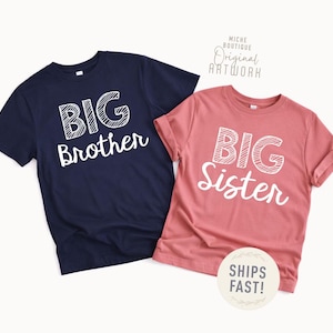 May include: Two short-sleeved t-shirts, one navy blue and one dusty rose. The navy shirt says "BIG Brother" in white, outlined text. The dusty rose shirt says "BIG Sister" in the same style. The shirts are for siblings.