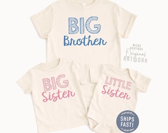 May include: Three cream-coloured t-shirts and a onesie with text. The largest shirt says "BIG Brother" in blue, the next says "BIG Sister" in pink, and the onesie says "LITTLE Sister" in pink. The shirts have short sleeves.