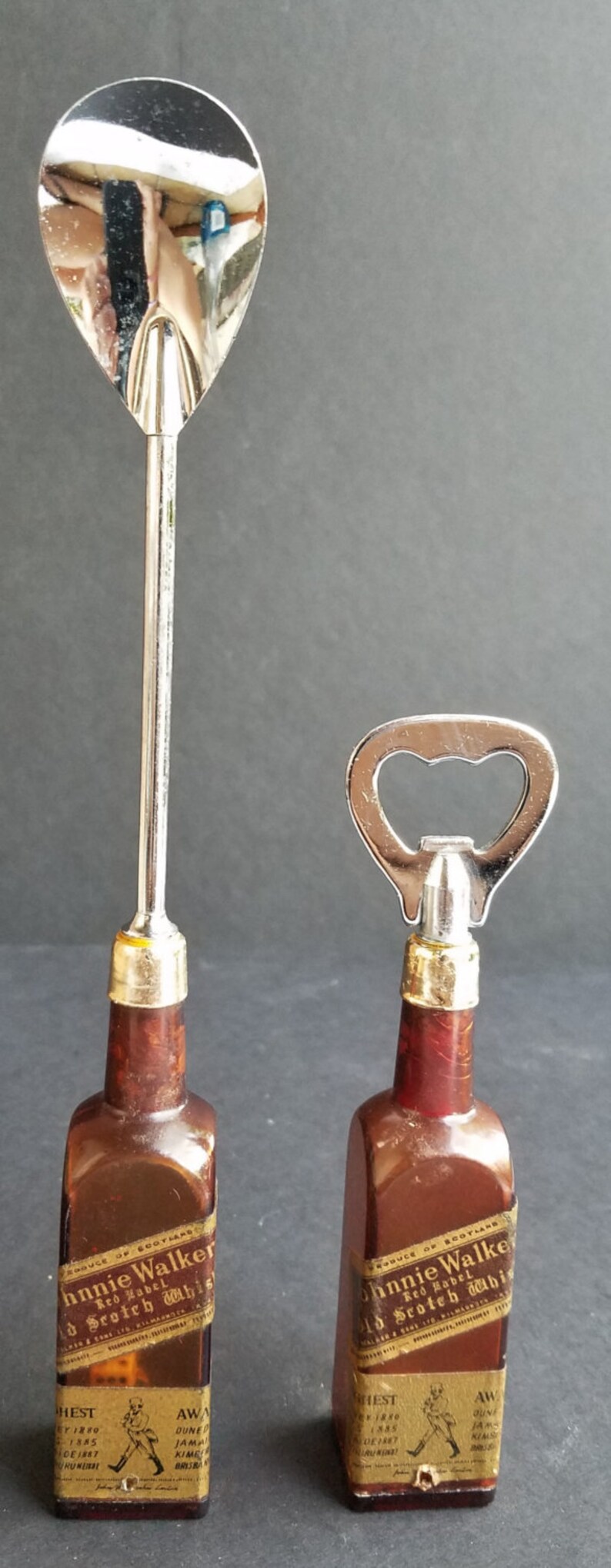 May include: Two miniature glass bottles shaped like liquor bottles with silver bottle openers attached. The bottles are brown and have labels that read "Johnnie Walker Red Label Old Scotch Whisky".