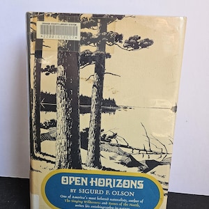 Puede incluir: Un libro titulado "Open Horizons" de Sigurd F. Olson. La portada presenta una ilustración en blanco y negro de árboles altos y un lago. El libro es del sistema de bibliotecas del condado de Orange.