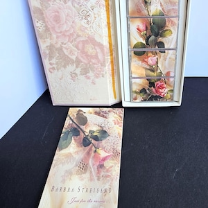 Könnte beinhalten: Eine dekorative Schachtel und eine Karte mit einem floralen Design mit rosa Rosen und Spitze. Die Schachtel ist geöffnet und zeigt eine Reihe gerahmter Rosenbilder. Auf der Karte steht "Barbra Streisand Just for the record..."