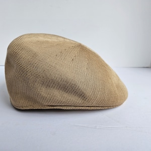 May include: A tan knitted newsboy cap with a rounded crown and a flat brim.