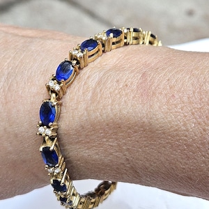 Blue Rhinestone Goldtone Metal Tennis Bracelet with Small Clear Rhinestone Accents by Avon
