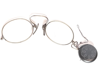 Gafas antiguas tipo pince-nez con montura de alambre y broche retráctil decorativo.