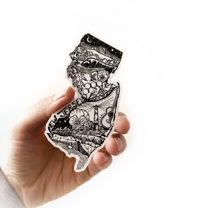 May include: Black and white illustration of the state of New Jersey with various icons and symbols representing the state, including a lighthouse, a guitar, a beehive, and a crescent moon. The text "NEW JERSEY" is written in a stylised font.