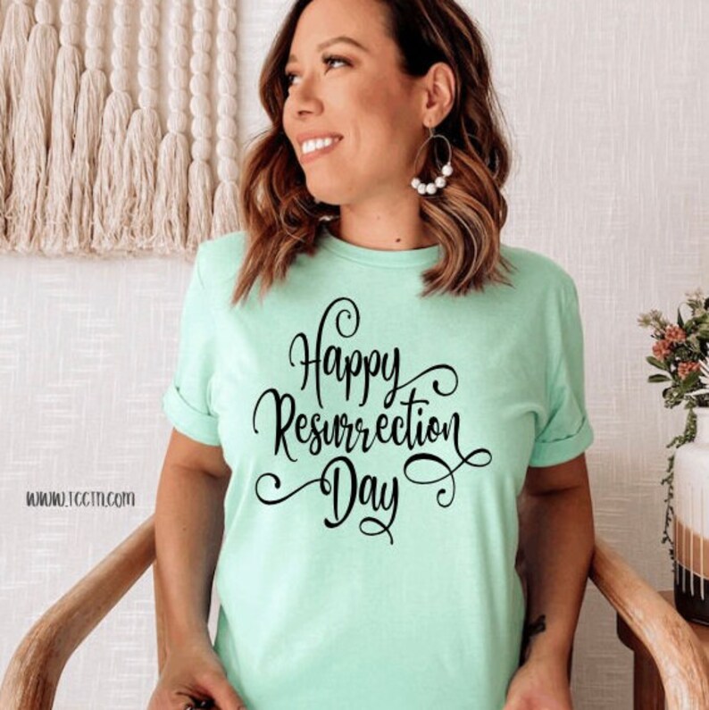 May include: A light green t-shirt with the words "Happy Resurrection Day" in black script. The shirt has rolled-up sleeves and is being worn by a person. The website address www.10ctm.com is visible on the shirt.
