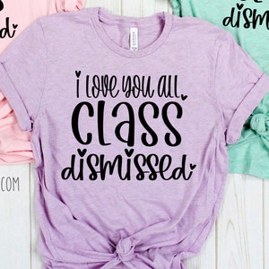May include: A lavender t-shirt with the text "I love you all. Class dismissed." in black lettering with hearts.