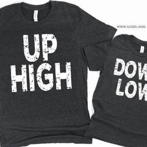 May include: Two gray t-shirts with white text. The first shirt says 'UP HIGH' and the second shirt says 'DOWN LOW'.