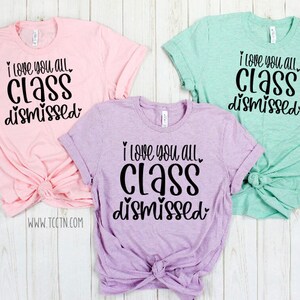 May include: Three t-shirts with the text "I love you all. Class dismissed." in black lettering on a pink, purple, and light green background.