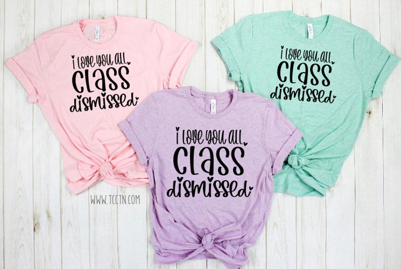 May include: Three t-shirts with the text "I love you all. Class dismissed." in black lettering on a pink, purple, and light green background.