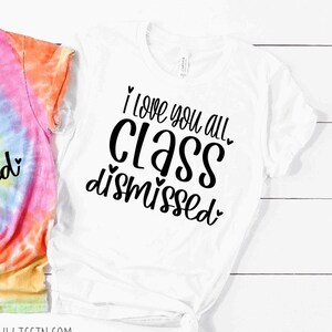 May include: White t-shirt with black text that reads "I love you all class dismissed" with hearts around the words.