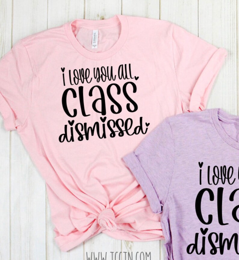 May include: Two pink and purple t-shirts with black text that reads "I love you all class dismissed" with hearts around the words.