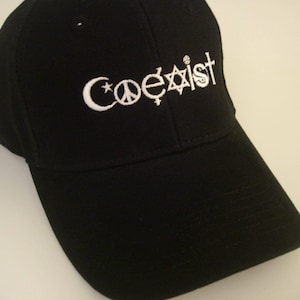 May include: Black baseball cap with a white embroidered design that says "Coexist" with symbols for peace, a star, a crescent moon, a cross, and a Star of David.