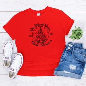 May include: Red t-shirt with a black graphic of Cinderella's castle and the text "Walt Disney World 2020 Magic Kingdom 20".