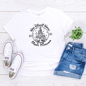 May include: White t-shirt with a black and white graphic of Cinderella's castle with the text "Walt Disney World 2020 Magic Kingdom 20" in a circle around the castle.