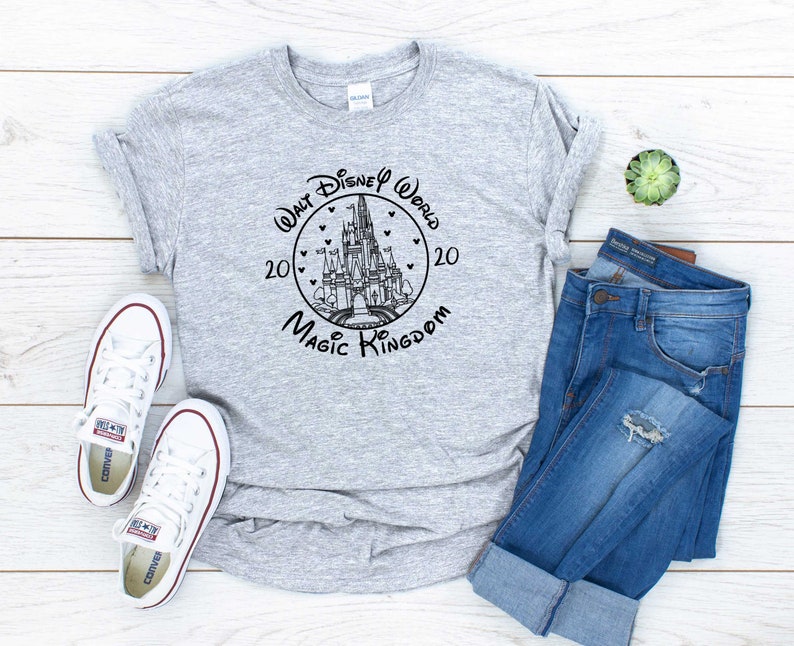 May include: A gray t-shirt with a black and white graphic of Cinderella's castle in a circle with the text "Walt Disney World 2020 Magic Kingdom".