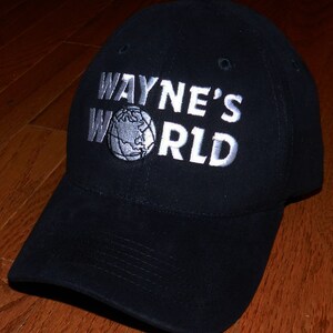 May include: A black baseball cap with a white embroidered logo that says "Wayne's World" with a globe graphic.