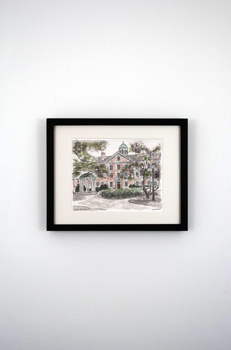 May include: A black framed print of a watercolor illustration of a brick building with a green roof and a cupola. The building is surrounded by trees and a small garden. The text "Old East, UNC Chapel Hill" is printed below the image.
