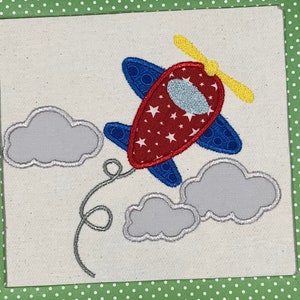 May include: A red, white, and blue airplane with a yellow propeller flying above two gray clouds. The airplane has stars on it.