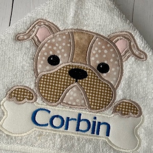 May include: White hooded towel with a brown and white embroidered bulldog holding a bone with the name Corbin embroidered on it.