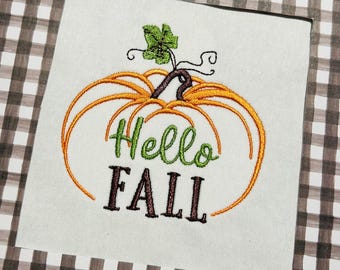 Op de afbeelding: Borduurwerk met een pompoen met een groene steel en bladeren, en de tekst "Hello Fall" in groene en bruine letters.